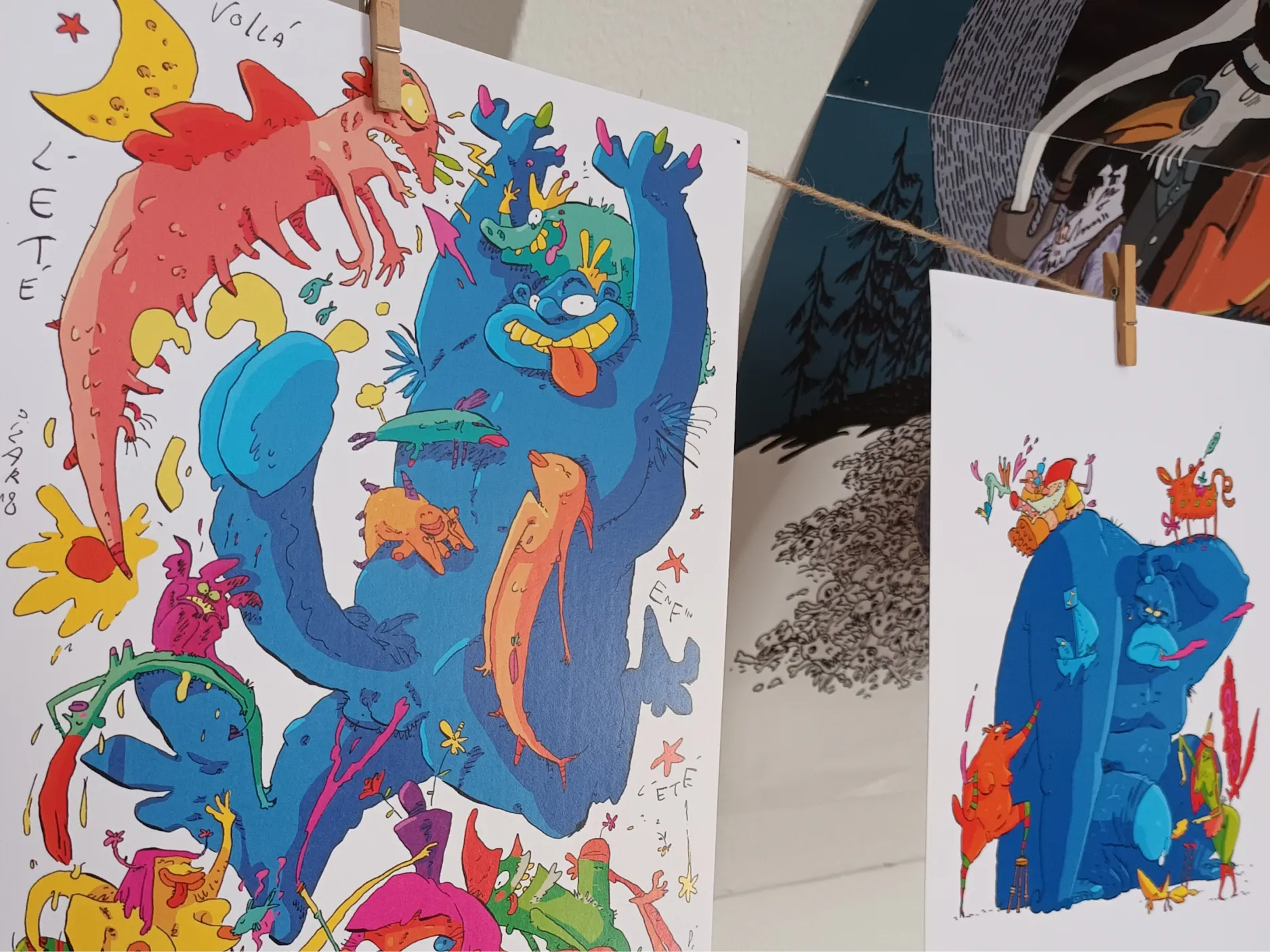 Fotografija dveh razstavljenih ilustracij barvitih pošasti